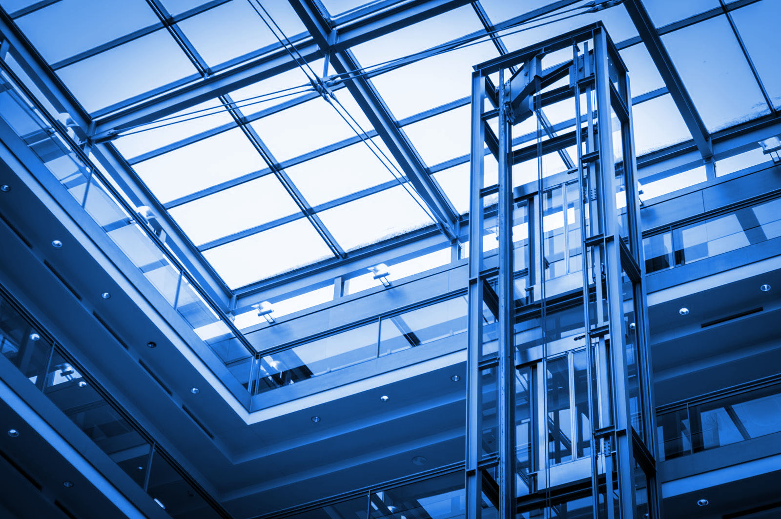 Átrio de prédio moderno com estrutura de elevador em vidro